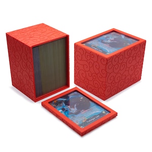 May include: A bright red rectangular card storage box featuring a raised swirl pattern on its exterior. The set includes a vertical deck holder filled with cards and a matching red lid with a clear window displaying a Trafalgar Law game card.