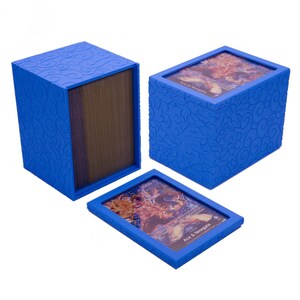 May include: A blue rectangular card storage box with a textured swirl pattern on the exterior. The box features a removable lid with a clear window displaying a trading card labeled Ace & Newgate. A stack of cards is visible inside the open box.