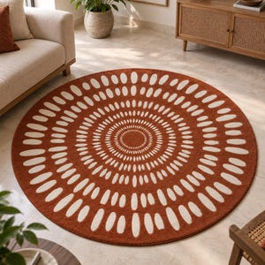 May include: A circular area rug featuring a deep terracotta orange background with a repeating pattern of white, elongated oval shapes arranged in concentric circles radiating outward from a solid circular center point.