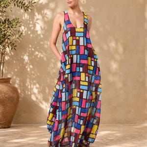 May include: A sleeveless maxi dress featuring a vibrant geometric pattern of rectangular blocks in shades of bright yellow, sky blue, magenta, and deep maroon, separated by thin black grid lines, with a scoop neckline and a loose, flowing silhouette.