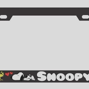 Peut inclure: Un cadre de plaque d'immatriculation rectangulaire noir avec un graphique de l'oiseau jaune Woodstock et du chien blanc Snoopy allongé avec deux cœurs rouges entre eux. Le nom Snoopy est imprimé en grosses lettres blanches en bas.