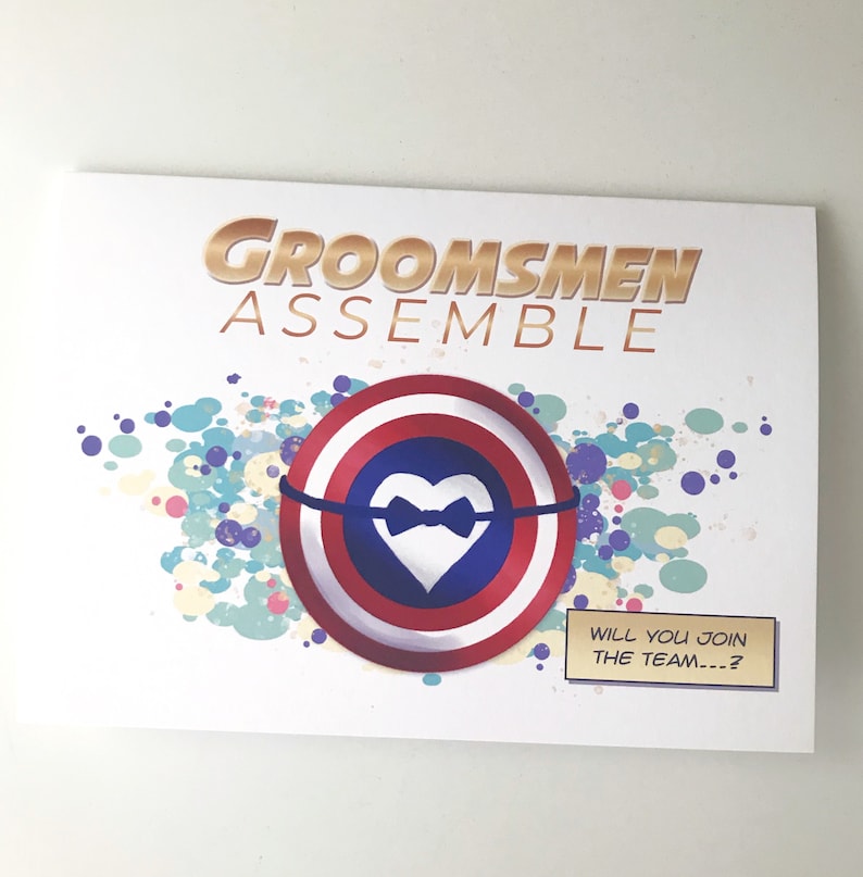 May include: A white card with the text "Groomsmen Assemble" in gold letters. A red, white, and blue shield with a white heart and a black bowtie is in the center of the card. The text "Will you join the team...?" is in a white speech bubble.