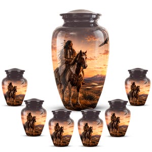 May include: A collection of seven dark-toned metal cremation urns featuring a printed scene of a person in traditional attire riding a horse across a landscape at sunset, with a flying eagle in the sky and a matching lid on each vessel.