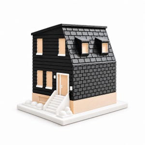 May include: A miniature model of a house featuring black horizontal siding and a black shingled roof with two dormer windows. The structure has light beige window frames and a door, a white staircase leading to the entrance, and a white base foundation.
