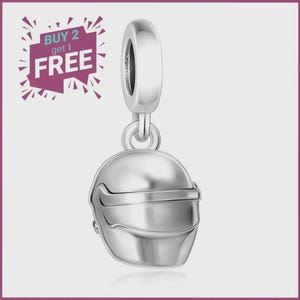 Peut inclure: Un charm en métal argenté en forme de casque de course avec une visière lisse et arrondie et une bélière circulaire sur le dessus pour la fixation. Le charm présente une finition polie et inclut un texte superposé BUY 2 get 1 FREE.