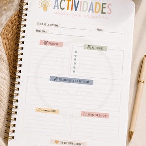 Puede incluir: Un cuaderno de planificación de actividades con encuadernación en espiral y portada blanca con el texto ACTIVIDADES ideas que inspiran. La página incluye secciones para título, fecha, área, objetivos, materiales, desarrollo y una valoración.