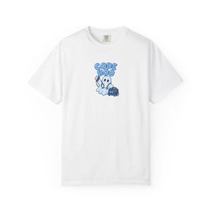 May include: A white short-sleeve t-shirt featuring a central graphic of a cartoon ghost dressed as a medical professional with a stethoscope, holding a telephone receiver, and carrying a heart monitor. The text CODE BOO is printed in blue.