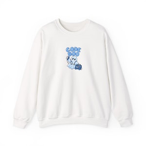 May include: A white crewneck sweatshirt featuring a central graphic of a ghost dressed as a medical professional with a stethoscope, holding a phone, and standing next to a heart monitor. The text CODE BOO is printed in blue above the ghost.
