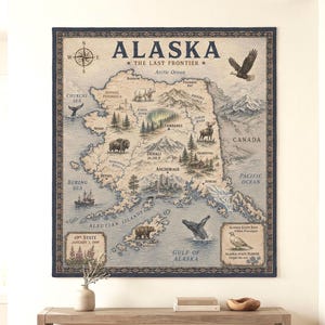 Puede incluir: Un tapiz de pared tejido que presenta un mapa detallado de Alaska, etiquetado como The Last Frontier. El mapa muestra puntos de referencia geográficos, ilustraciones de vida silvestre y texto que incluye 49th State January 3, 1959 y Alaska State Bird.
