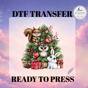 May include: A DTF transfer sheet featuring a Christmas tree illustration with a squirrel, owl, rabbit, and two birds. The design includes red gift boxes, pinecones, and stars. Text reads DTF TRANSFER and READY TO PRESS with a logo.