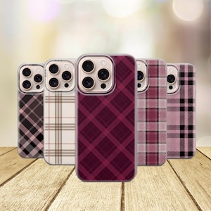 May include: Five smartphone cases arranged in a row, each featuring a distinct plaid or tartan pattern. The designs include variations of black, white, beige, deep burgundy, and soft pink, all showcasing a triple-lens camera cutout on the back.