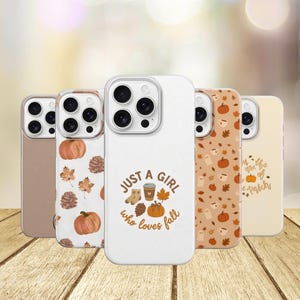 Op de afbeelding: Vijf smartphonehoesjes op een rij. Eén is effen beige, één heeft pompoenen en dennenappels, één is wit met de tekst 'JUST A GIRL who loves fall' en herfsticonen, één heeft een patroon van pompoenen en spookjes, en één is crèmekleurig met tekst.