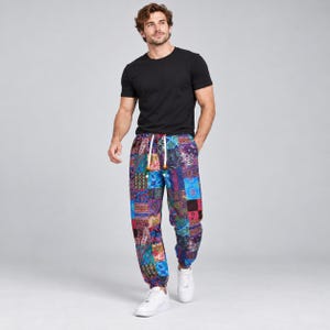 May include: A black short-sleeved t-shirt paired with loose-fitting pants featuring a vibrant, multi-colored patchwork pattern of paisley and floral designs. The pants include a white drawstring waist with wooden beads and white sneakers.