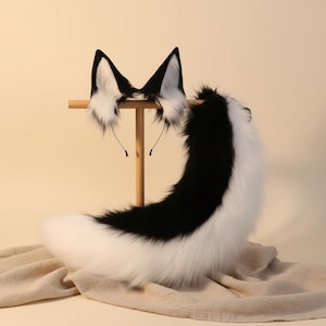 Peut inclure: Un ensemble composé d'oreilles d'animal en fausse fourrure sur un serre-tête noir fin et d'une longue queue incurvée assortie en fausse fourrure. Les oreilles et la queue présentent un motif bicolore avec de la fourrure noire sur le dessus.