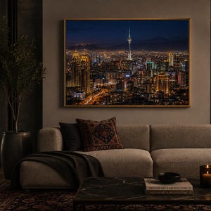 May include: A rectangular wall art print featuring a night cityscape of Tehran with the Milad Tower illuminated against a dark blue sky, framed in a thin gold border and displayed above a beige sofa in a dimly lit room setting.