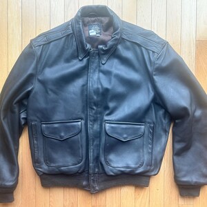May include: A black leather bomber jacket with a zipper closure, two flap pockets, and a ribbed knit collar and cuffs.