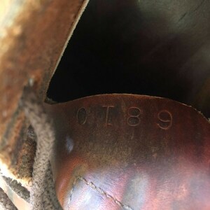 May include: Close-up of the inside of a brown leather boot with the number "0189" stamped on the leather.