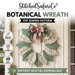 Op de afbeelding: Een botanisch krans PDF-naaipatroon van StitchedSafariCo met doorgestikte stoffen bladeren in saliegroen en een bloemenprint. De krans is versierd met een mauve satijnen lintstrik en een houten kraal, weergegeven op een witte deur.