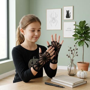 May include: A pair of black fingerless gloves featuring an intricate, open-work crochet spiderweb pattern. The gloves extend from the knuckles to the wrists, showcasing a detailed web design that radiates from the center of the hand.