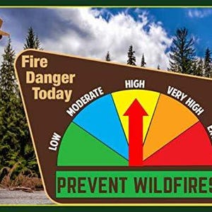 May include: Smokey Bear stands beside a fire danger sign. The sign displays a color-coded fire danger scale, ranging from low to extreme, with a red arrow pointing towards the high danger level. The sign reads "Fire Danger Today" and "Prevent Wildfires."