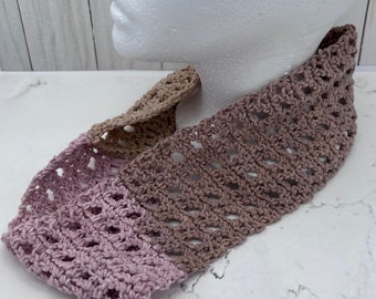 May include: A handmade crochet headband in shades of mauve, tan, and brown. The open weave design is visible, and the headband is displayed on a mannequin head. The headband is a fashion accessory.