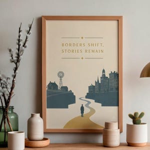 May include: A framed wall art print featuring a cream background with the text "BORDERS SHIFT, STORIES REMAIN" in gold. The illustration depicts a lone figure walking on a yellow path between a rural landscape with a windmill and a city skyline.