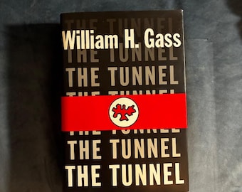 May include: A black book titled The Tunnel by William H. Gass with white text repeated on the cover. A bright red horizontal band wraps around the center, featuring a white circular emblem with a stylized red leaf-like graphic in the middle.