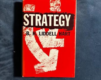 May include: A hardcover book titled Strategy by B. H. Liddell Hart. The cover features a bold red background with a large, distressed white arrow graphic pointing downward. The word Strategy is printed in white text on a black rectangular bar.