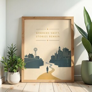 May include: A framed wall art print featuring a beige background with the text BORDERS SHIFT, STORIES REMAIN. The illustration depicts a lone figure standing on a path between a rural landscape with a windmill and a dense city skyline in dark blue.
