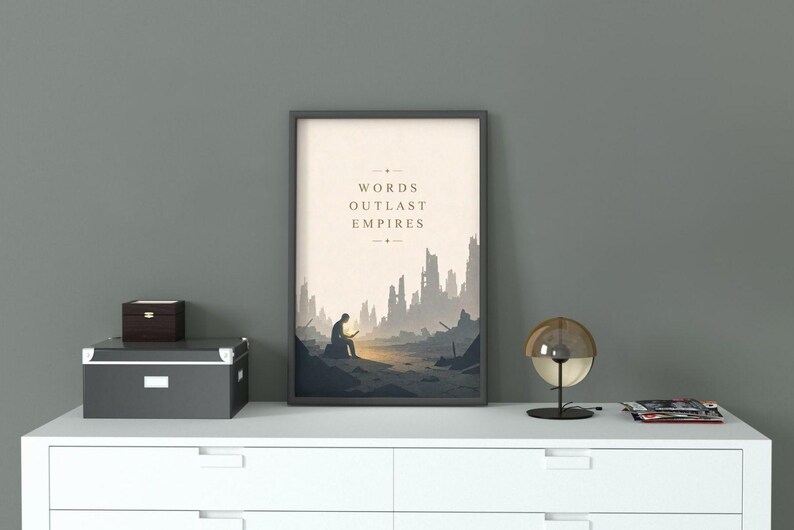 May include: A framed vertical wall art print featuring a beige background with the text "WORDS OUTLAST EMPIRES" centered above a dark silhouette of a person sitting on a rock in a desolate, ruined landscape with jagged, crumbling structures.