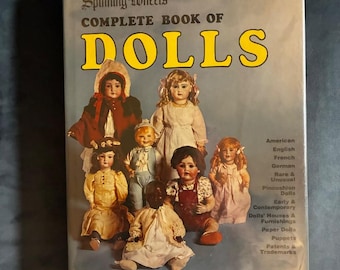 May include: A hardcover book titled Spinning Wheel's Complete Book of Dolls, edited by Albert Christian Revi. The cover features a group of antique dolls in various outfits and lists topics including American, English, French, and German dolls.