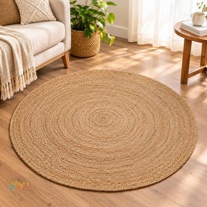 May include: A round, natural-colored jute rug featuring a tightly woven, concentric circular pattern. The rug is constructed from braided plant fibers, displaying a consistent tan and beige texture across its entire flat, circular surface.