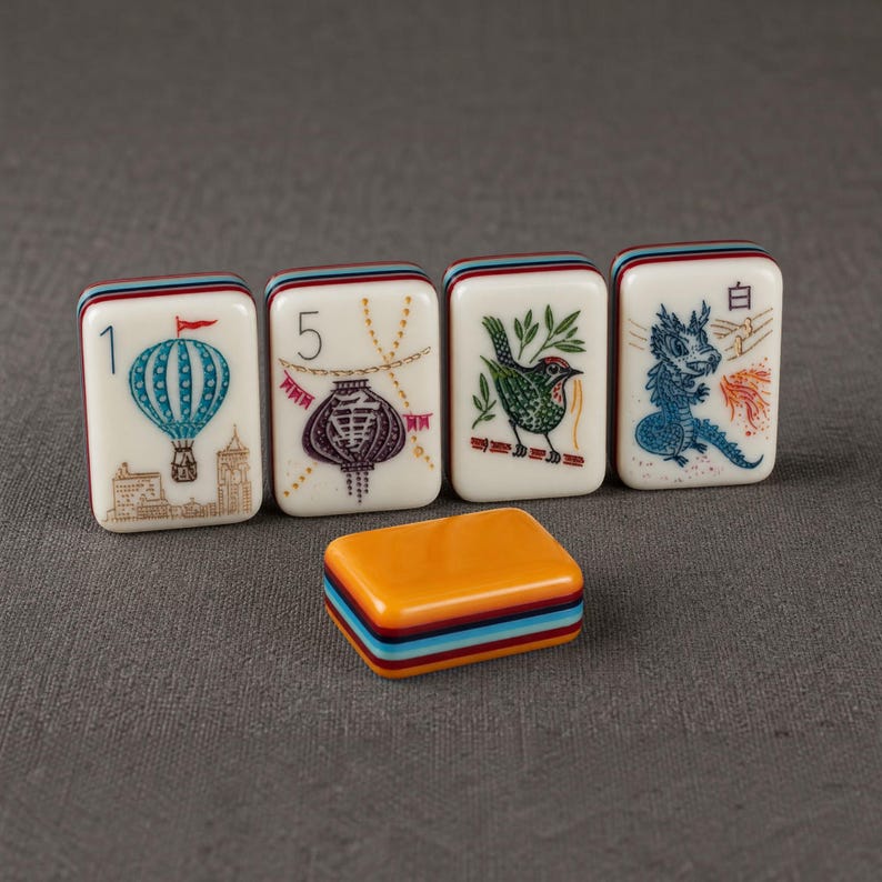 Puede incluir: Cuatro fichas de mahjong rectangulares con caras de color crema que muestran ilustraciones de un globo aerost&aacute;tico azul, un farol morado, un p&aacute;jaro verde y un drag&oacute;n azul con el car&aacute;cter 白, adem&aacute;s de una ficha naranja s&oacute;lida con bordes.