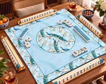 Può includere: Un tappetino da mahjong quadrato con sfondo azzurro e un'illustrazione circolare centrale di pavoni e rami fioriti. Il tappetino include quattro supporti dorati per tessere con tessere bianche da mahjong con segni rossi e neri.