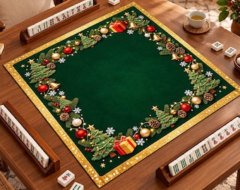 Può includere: Un tappetino da mahjong quadrato verde con un bordo festivo di rami di pino, ornamenti rossi e dorati, regali e campanelle dorate. Il tappetino ha un bordo glitterato dorato ed è posizionato su un tavolo di legno con tessere.