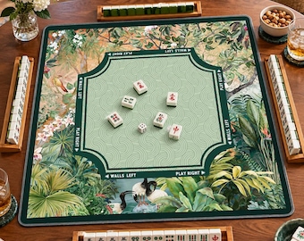 Peut inclure: Un tapis de mah-jong carré présentant une zone centrale vert clair avec des motifs de vagues et des bordures vert foncé marquées d'indications de jeu. Le tapis affiche un imprimé botanique luxuriant avec des feuilles tropicales et des tuiles.