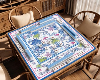 Può includere: Un tappetino da mahjong quadrato con sfondo bianco e una stampa botanica blu e rosa di pagode, palme e fenicotteri. Il tappetino è bordato da una cornice blu e rosa e contiene file di tessere da mahjong azzurre e tessere sparse.