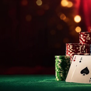 Può includere: Una pila di fiches da poker multicolori verdi, rosse, blu, nere e dorate, disposte ad altezze variabili. Due carte da gioco, l'Asso di Cuori e l'Asso di Picche, sono posizionate davanti alle fiches su una superficie in feltro verde.
