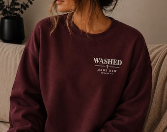 May include: A deep burgundy crewneck sweatshirt featuring white text on the upper left chest that reads WASHED, followed by a small cross symbol, the words MADE NEW, and the scripture reference ROMANS 6:4 in a clean, sans-serif font.