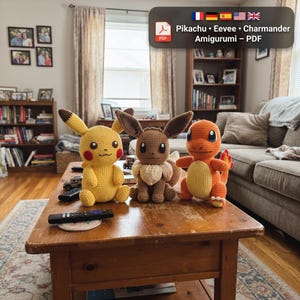 May include: Three crocheted amigurumi plush toys representing Pikachu, Eevee, and Charmander. The yellow Pikachu, brown Eevee, and orange Charmander are displayed on a wooden table. A digital file label reads: Pikachu • Eevee • Charmander Amigurumi – PDF.