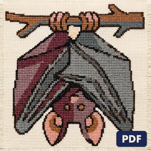 A finished hanging bat cross stitch piece, stitched and framed on a wall