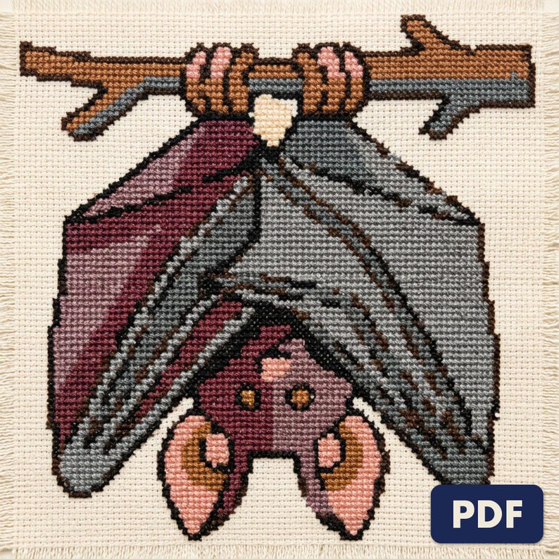 A finished hanging bat cross stitch piece, stitched and framed on a wall