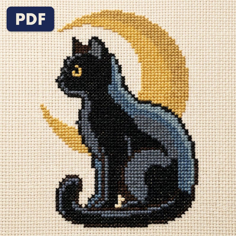 A finished black cat under a crescent moon cross stitch piece, stitched and framed on a wall