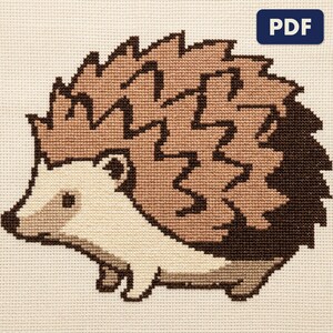 A finished a hedgehog cross stitch piece, stitched and framed on a wall