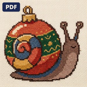 A finished a snail whose shell is a bauble cross stitch piece, stitched and framed on a wall