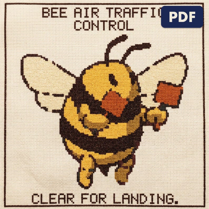 A finished bee air traffic control cross stitch piece, stitched and framed on a wall
