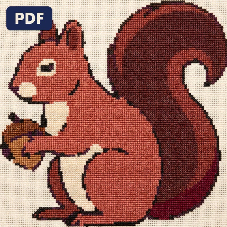 A finished a red squirrel cross stitch piece, stitched and framed on a wall