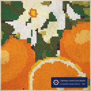 Close up of the an orange branch cross stitch design worked stitch by stitch, every cross and thread colour visible