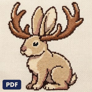 A finished jackalope cross stitch piece, stitched and framed on a wall