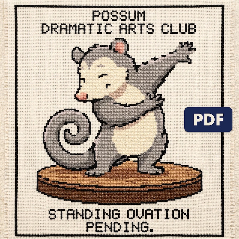 A finished possum dramatic arts club cross stitch piece, stitched and framed on a wall